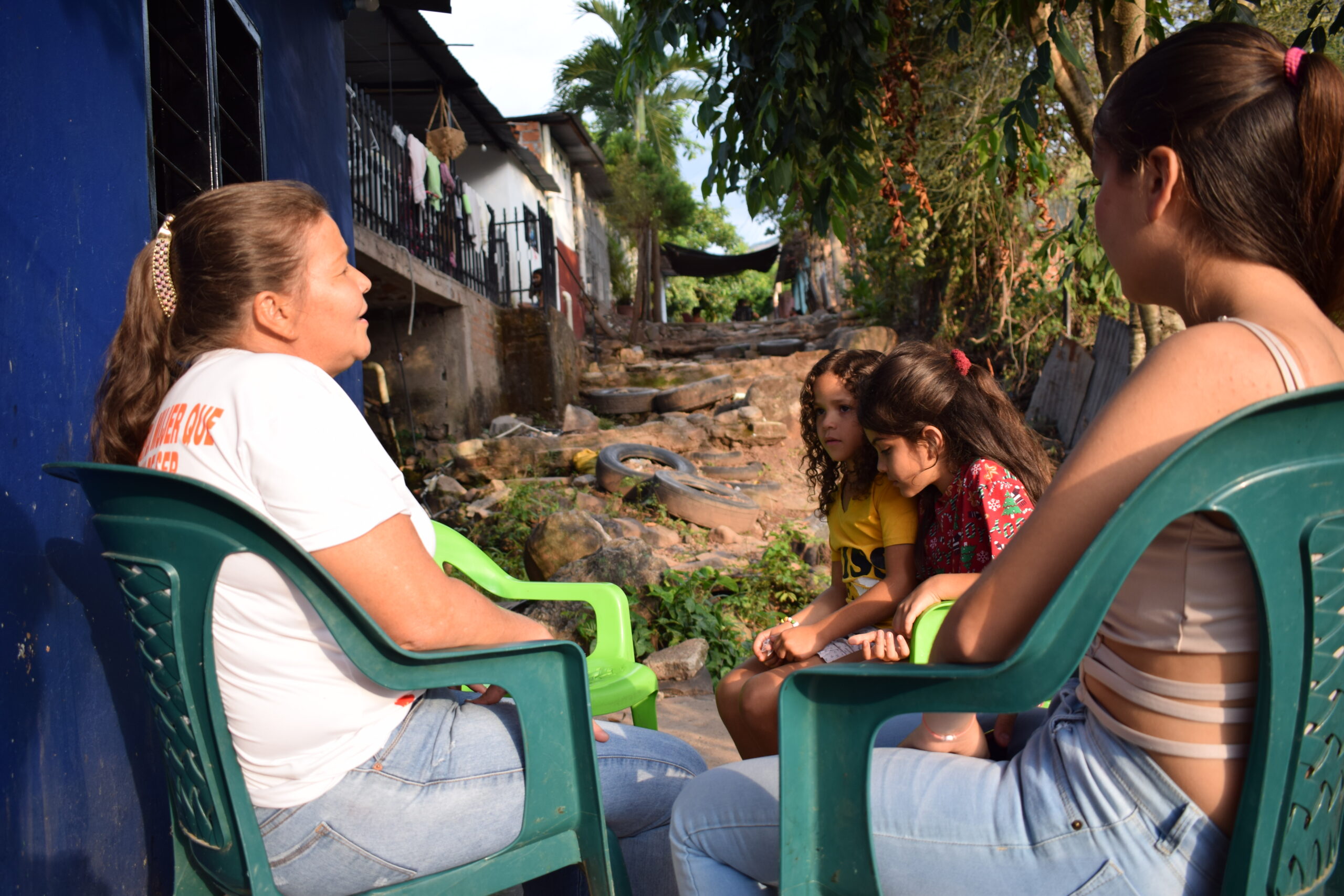 Magie Vergel cuenta su historia de vida. De derecha a izquierda le acompañan su hija Kelly, una niña del vecindario y su nieta, Sofía Bustos. FOTO: ALEX GUTIÉRREZ.